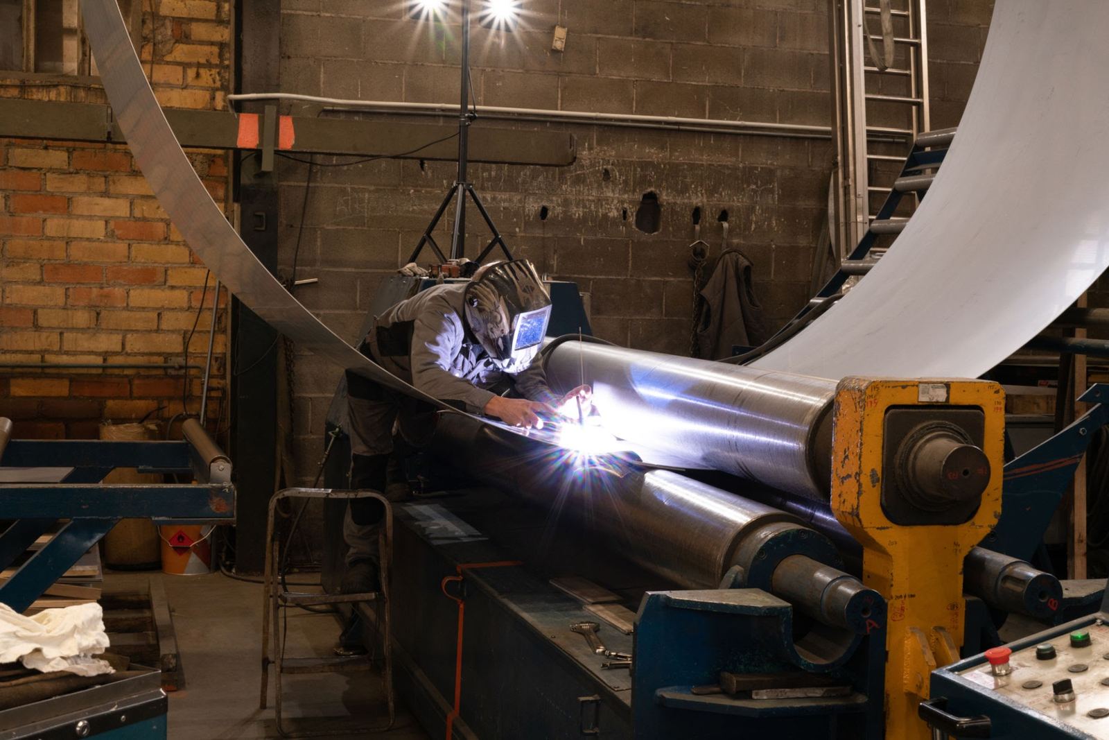 Workshop technician welding a rolled steel cylinder for Meyana Energy